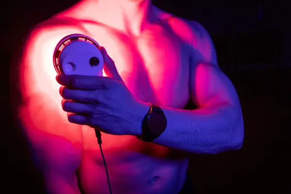 A man holding a SuperPalm light therapy device in his hands.